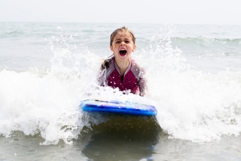 child on a boogie board wearing a wetsuit