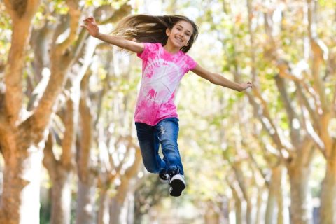 Tween pre-pubescent child jumping for joy through trees
