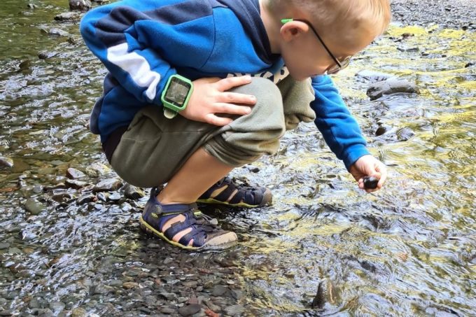 child in a stream wearing a pair of waterproof hiking sandals