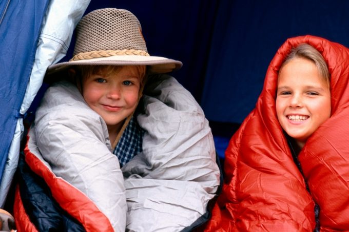 Two kids in a tent wrappe up in their sleeping bags