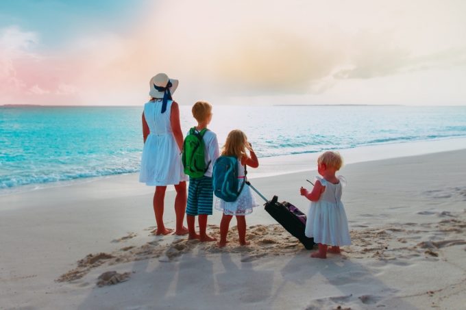 Family standing on a beach wearing backpacks