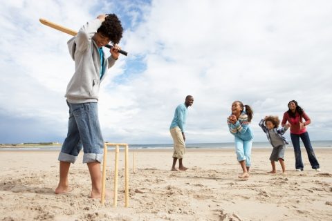 Family playing crciket on the beach - beach games for families