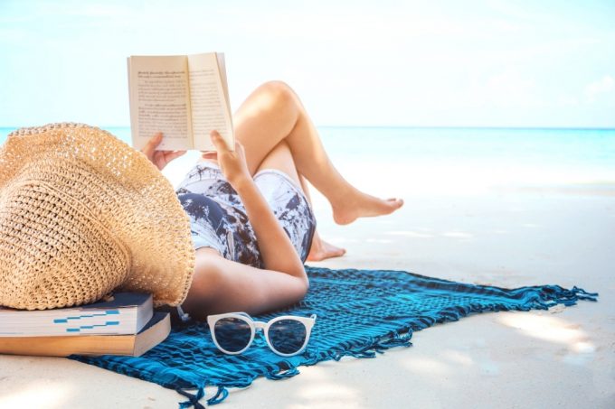 Lady relaxing on a beach mat reading a book