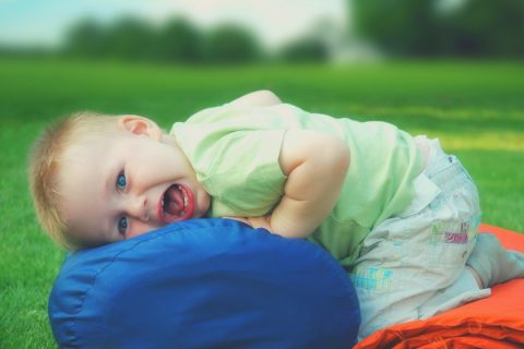 Toddler smiling lying on a sleeping bag camping