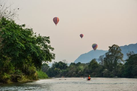 Hot air ballons over river with kayaks Laos