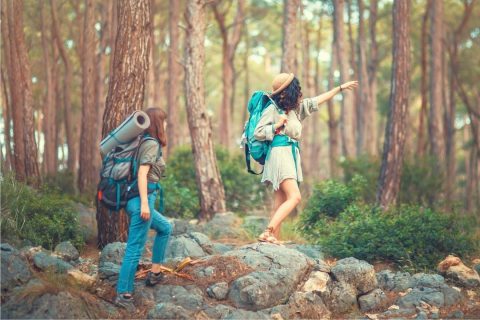 women with backpacks hiking through a forest