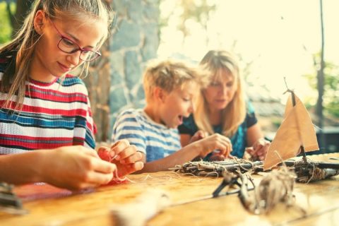 a grils and boy building nature crafts outside with their mother