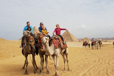 a family in front of the pyramids of giza on camel back