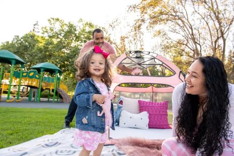 family playing in a park with a pink pop n go portable playpen