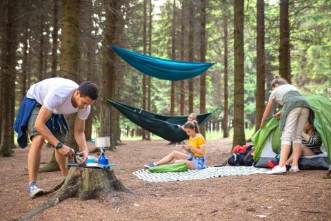 A family hammock camping in the woods