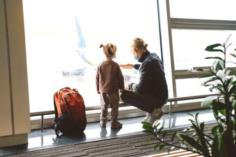 A mother with child at the airport looking at airplanes