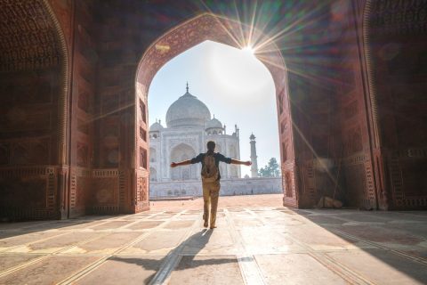 a man standing in sunsoaked archway looking at the Taj Mahal - tips for first time visitors to India