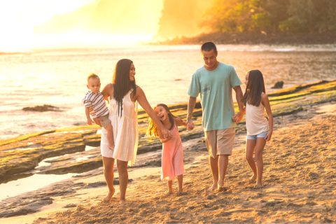 a happy family walking along a beach at sunset planning a perfect stress free family vacation