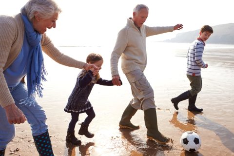 grandparents playing football on the beach with their grandchildren