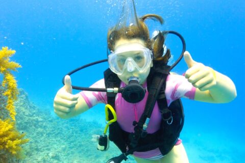 a girl in scuba diving gear giving a thumbs up