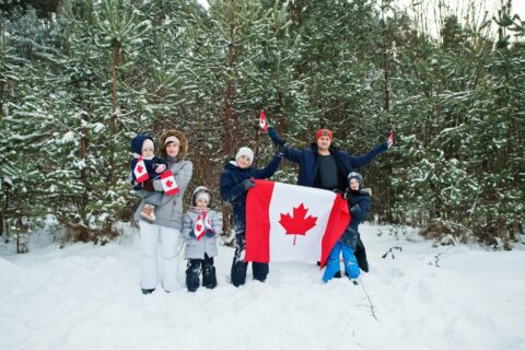 a family standing in the snow in canada with a canada flag
