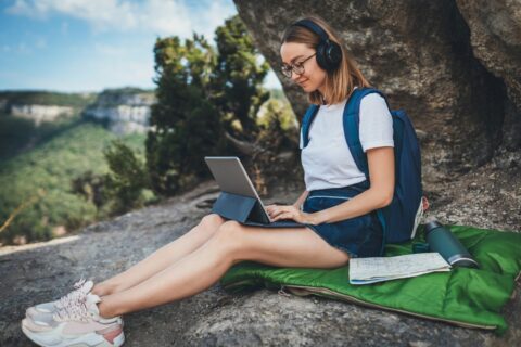 a girl working out in nature with a laptop and headphones on wearing a laptop backpack